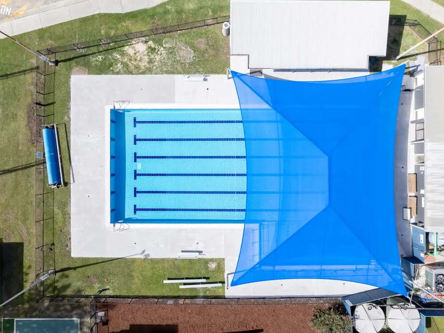 Aerial view of a refurbished lap pool with new lane tiles and shade sails